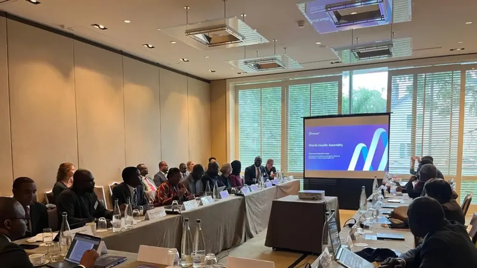 Government and partner representatives around a U-shaped table at an Axmed workshop, with an Axmed slide on the screen