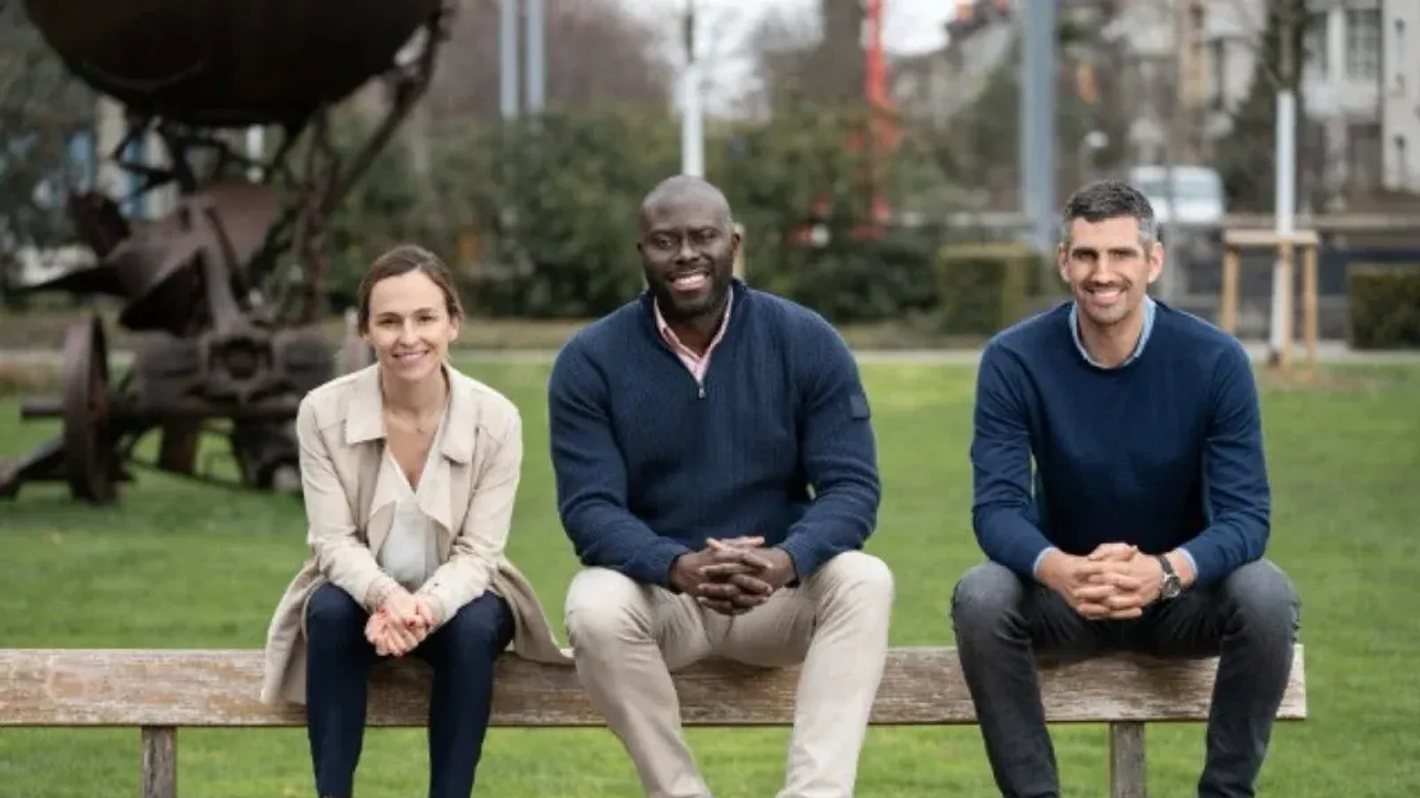 Axmed co-founders Sofia Radley-Searle, Emmanuel Akpakwu and Felix Ohnmacht seated together on a park bench